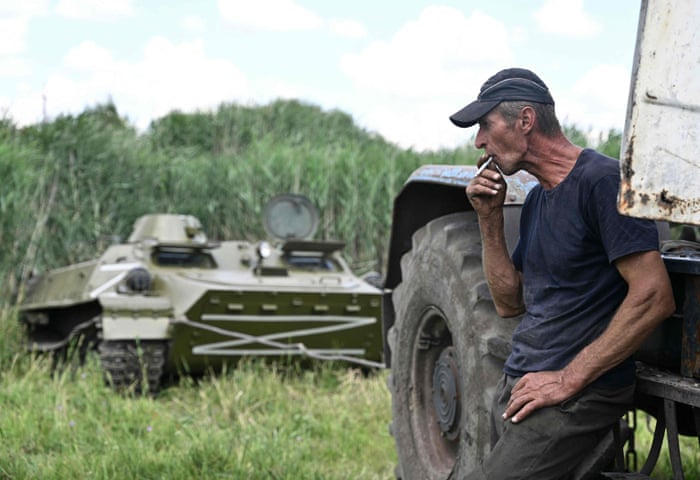 A Ukrainian farmer stops for a cigarette, with an abandoned Russian APC nearby, on a field near the village of Mala Rogan, Kharkiv region.