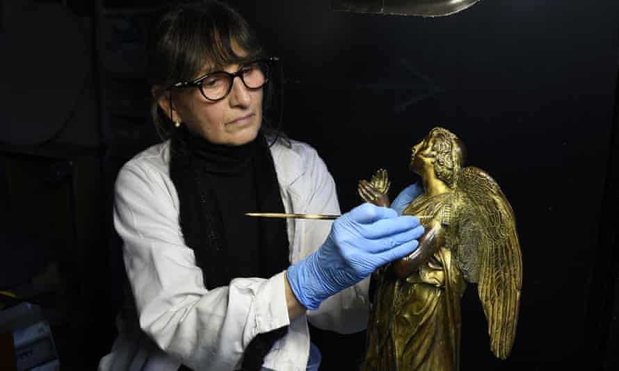 Una delle statue del fonte battesimale del Duomo di Siena è pulita da una penna di riccio.