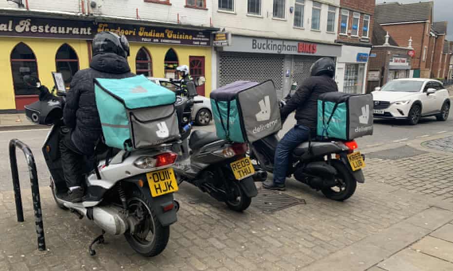 Deliveroo drivers on mopeds wait outside an Indian takeaway in Aylesbury, Buckinghamshire.
