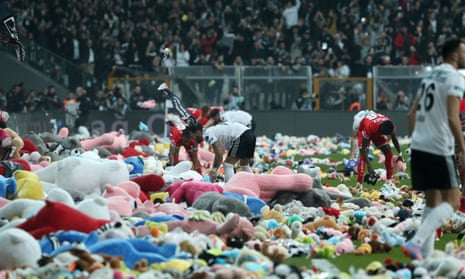 Besiktas and Antalyaspor players collect toys thrown on by fans during Sunday’s match.