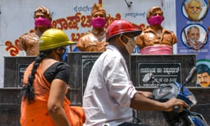 Motorists ride past the statues of Indian freedom fighter Subhas Chandra Bose (C), and actors in the Kannada cinema, Dr. Rajkumar (L) and Vishnuvardhan, wearing shawls on the face as protection against coronavirus, in Bangalore on 9 April 2020.