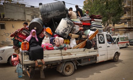 People sit on a truck piled high with various belongings