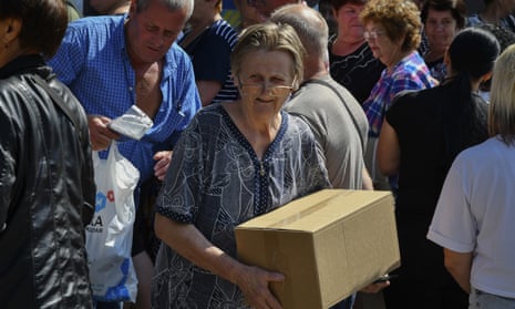 A woman carries a box after receiving humanitarian food aid in Zaporizhzhia, Ukraine, Tuesday, Aug. 2, 2022. (AP Photo/Andriy Andriyenko)