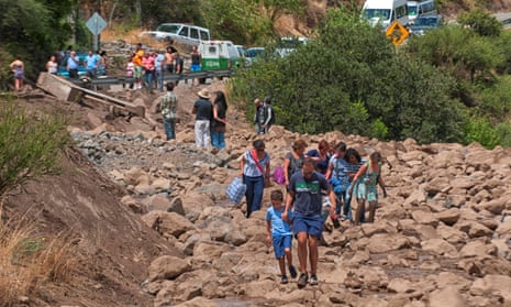 People walk along a damage road after a flood near Santiago.