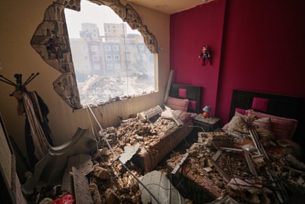A bedroom with its window blown away and rubble on the beds