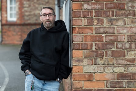 Bryan Stokell poses for a picture while leaning against a brick wall