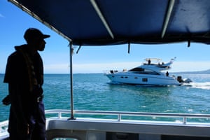 A crew member of police boat Veiqaravi watches a pleasure craft motor past in Nadi Bay