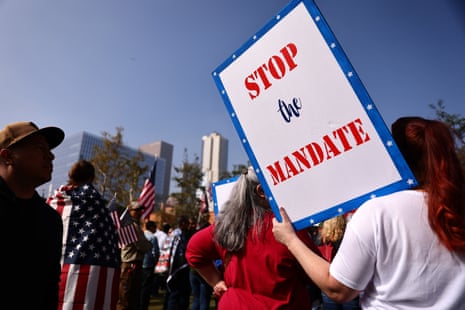 Demonstrators gather in Los Angeles at a March for Freedom rally on 8 November to protest the vaccine mandate, one carrying a "Stop the mandate" sign.
