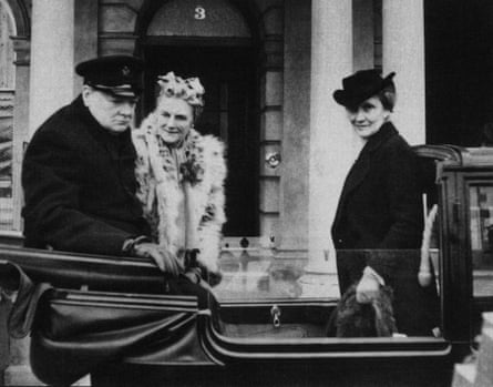 A black and white photo of Winston Churchill in a black coat and hat, his wife Clementine in a fur coat, and Nancy Astor in a black coat and hat, all in a carriage