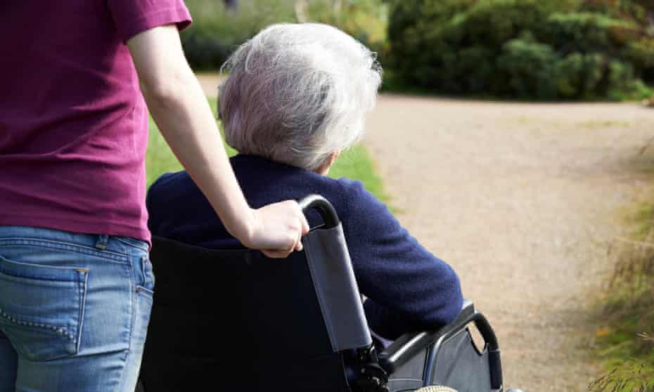 An elderly woman being pushed in a wheelchair by a younger woman