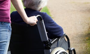 A woman pushing her mother in a wheelchair.