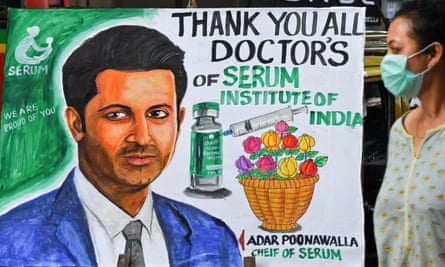 A woman walks past a painting welcoming the Covid-19 vaccination programme with a portrait of Adar Poonawalla