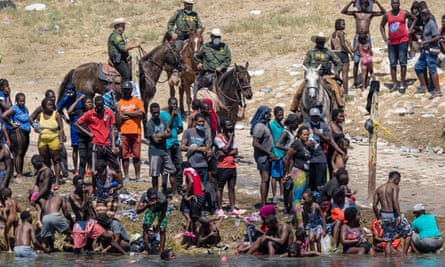 Mounted US border patrol agents watch Haitian immigrants on the bank of the Rio Grande in Del Rio, Texas, on Monday.