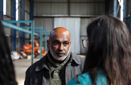 Thevan Pillay stands in an industrial unit talking to a woman.
