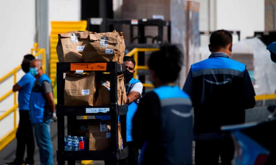 An Amazon delivery driver pushes a cart of groceries to load into a vehicle outside of a distribution facility on 2 February 2021 in Redondo Beach, California