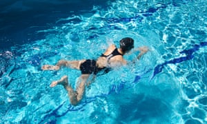 Woman with swimsuit swimming in a blue water pool