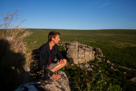 Land activist Guy Shrubsole kneeling on a rock on Dartmoor