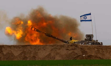 A tank flying an Israeli flag fires a shell with a bright muzzle flash.