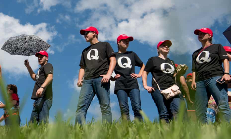 Supporters of Donald Trump wearing QAnon t-shirts wait in line before a campaign rally.