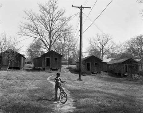 Young boy on his bike in front of small houses in the deep south in the 1980s