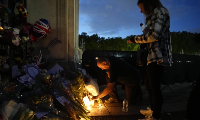 A man lights a candle at the gates of Buckingham Palace on Saturday