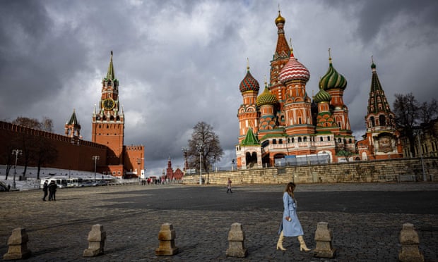 Une femme marche à l'extérieur du Kremlin, de la place Rouge et de la cathédrale Saint-Basile dans le centre de Moscou