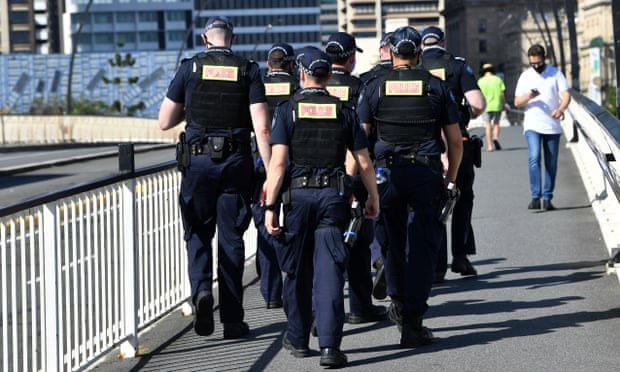 A group of Queensland Police officers are seen walking across the Victoria Bridge in Brisbane