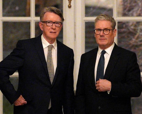Starmer and Mandelson in dark suits stand side by side in front of windows