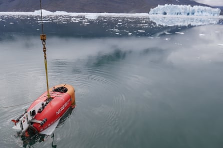 The red Nereid Under Ice submersible on the surface of icy waters