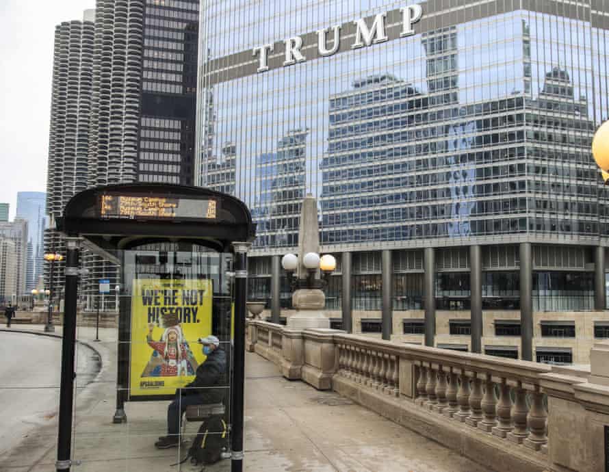A man sits in a covered bus shelter near the Trump International Hotel & Tower in Chicago, Illinois, in January.