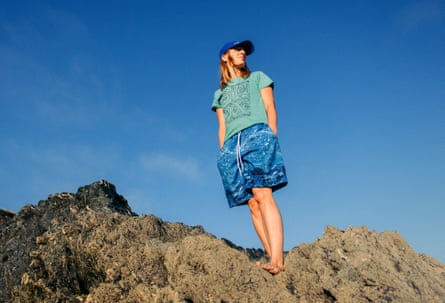 She wears very baggy blue board shorts with a watery pattern, and a faded green t-shirt