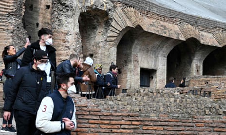 Tourists in Rome wearing respiratory masks visit the Coliseum.