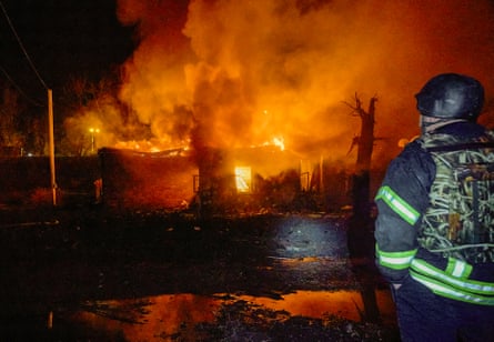 A rescue worker stands in front of a destroyed residential building in Kharkiv