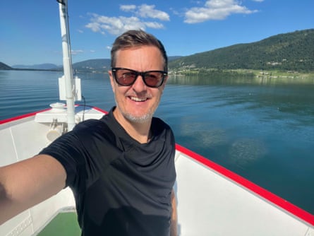 Smiling youngish man with sunglasses on a boat on a Swiss lake