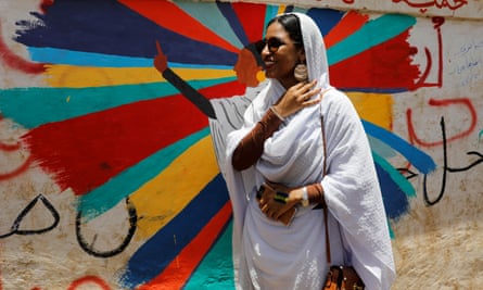 Alaa Salah stands in front of a mural depicting her in front of the defence ministry in Khartoum on 20 April.