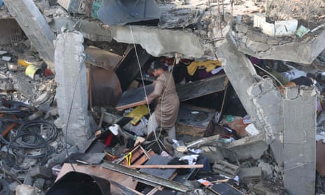 A man salvages objects amid rubble of a school hit during an Israeli strike before the start of the truce