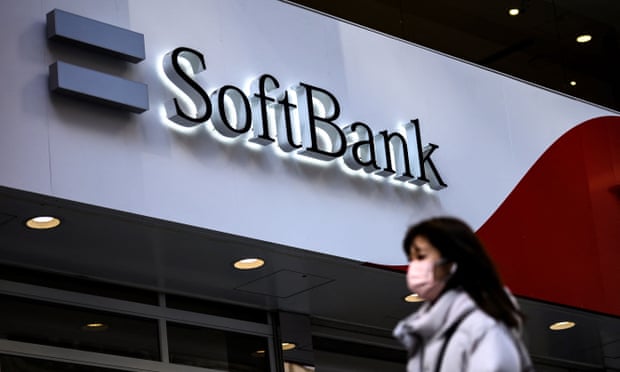 A pedestrian walks past the logo for telecom and investment giant SoftBank Group