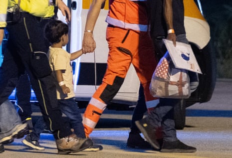 A child from Gaza holds the hand of a medic as he is evacuated from Gaza.