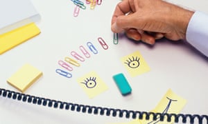 An office worker makes a happy face from stationery