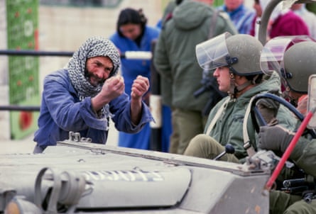 emotional man in keffiyeh speaks to soldiers in helmets