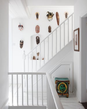 The white stairwell hung with totemic masks.