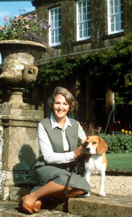 A woman in a tweedy waistcoat and skirt with sensible shoe and side parted bobbed hair with a beagle dog