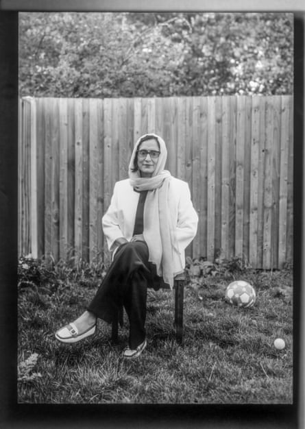 A woman sitting on a chair in a garden.