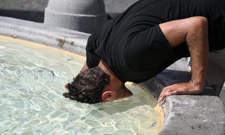 A man puts his head in the water to cool off at the fountain in Piazza del Popolo in Rome during the heatwave in July.