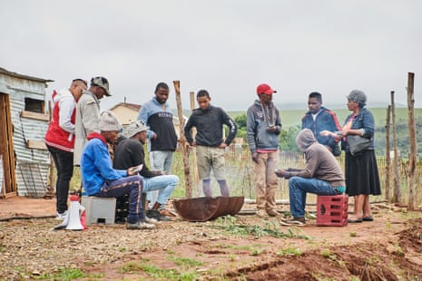 Sindi Matashi (far left) and Maria Mdakana (far right), who are literacy trainers for the Treatment Action Campaign, talk to a group of men on the road outside Belford Village in the Eastern Cape, introducing them to the ModernArt talking book about starting treatment for HIV.