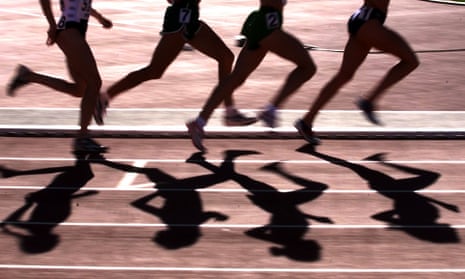 Women's 5,000m runners cast shadows on a running track