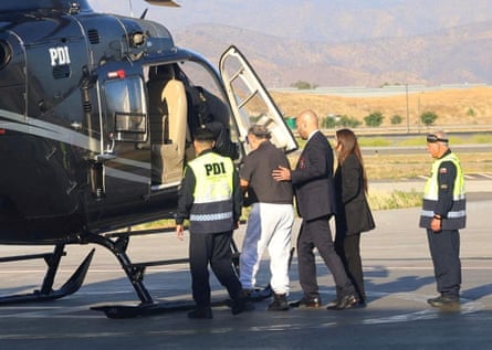 Officials lead an older man to a helicopter on a landing pad