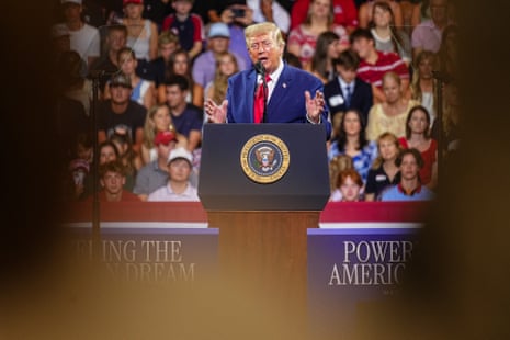 a man in suit speaks in front of a microphone to crowd