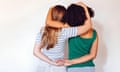 Rear view two teen girls best friends holding hands behind back and hugging<br>2M6XDJC Rear view two teen girls best friends holding hands behind back and hugging