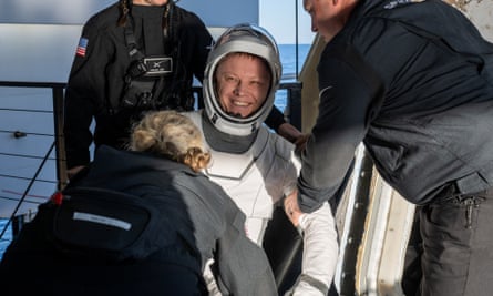 Roscosmos cosmonaut Aleksandr Gorbunov is helped out of a SpaceX Dragon spacecraft.